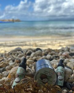 Les produits de beauté : sérum calendulaire, chantilly karite coco ricin et huile à barbe sont posés sur le bord de plage.